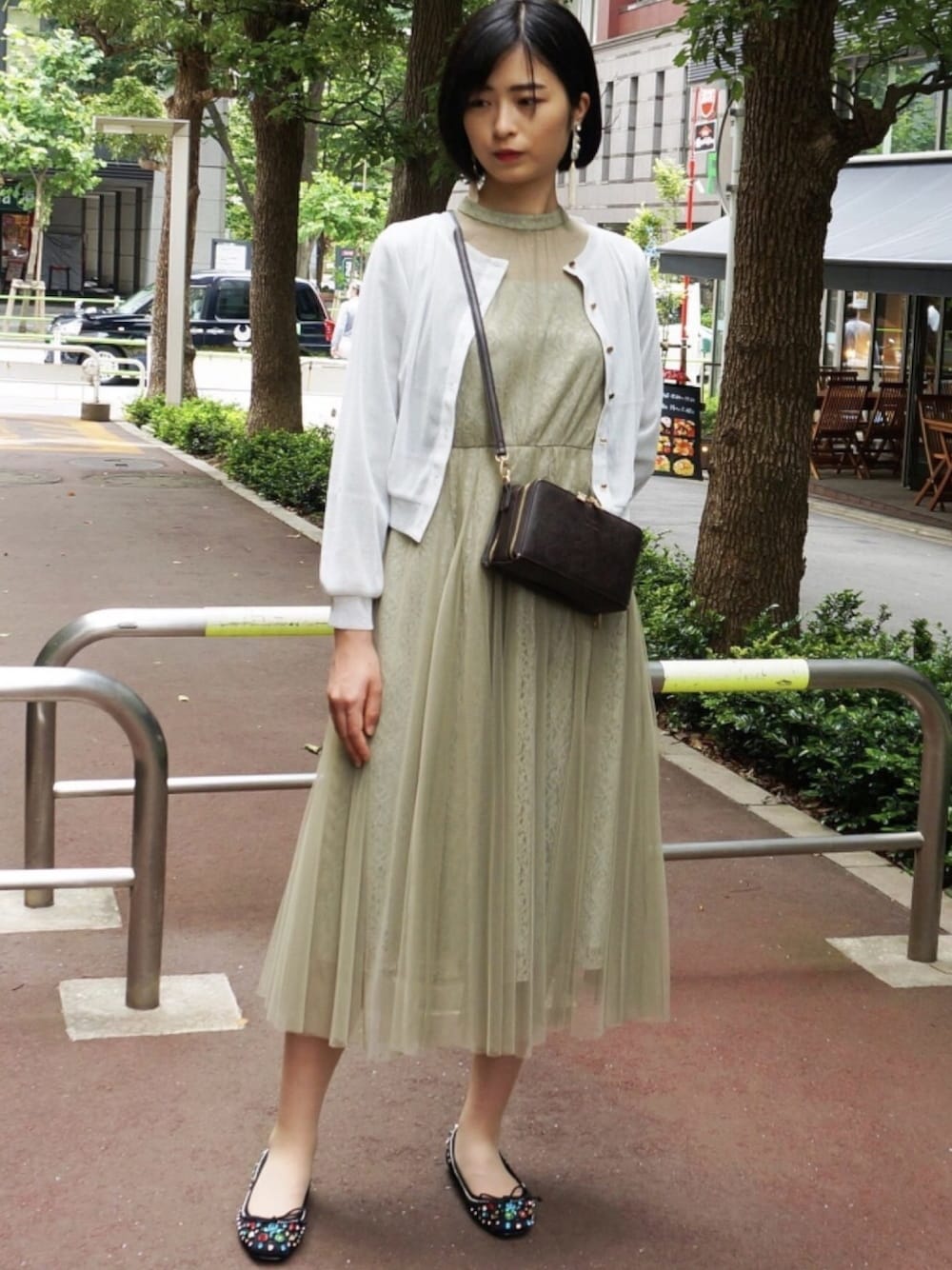 シルバー系のカーディガン/ボレロ、グリーン系のドレス、ブラック系のパンプスを着用したレディースの冬コーディネートの1枚目の写真