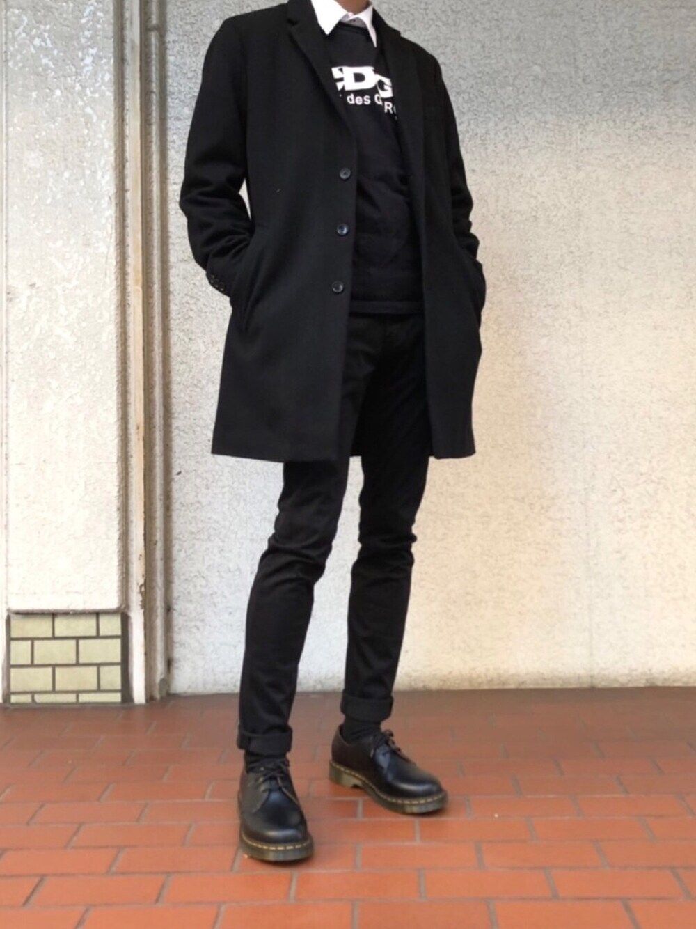 ブラック系のブーツ、ブラック系のチェスターコート、ブラック系のTシャツ/カットソーを着用したメンズの冬コーディネートの1枚目の写真