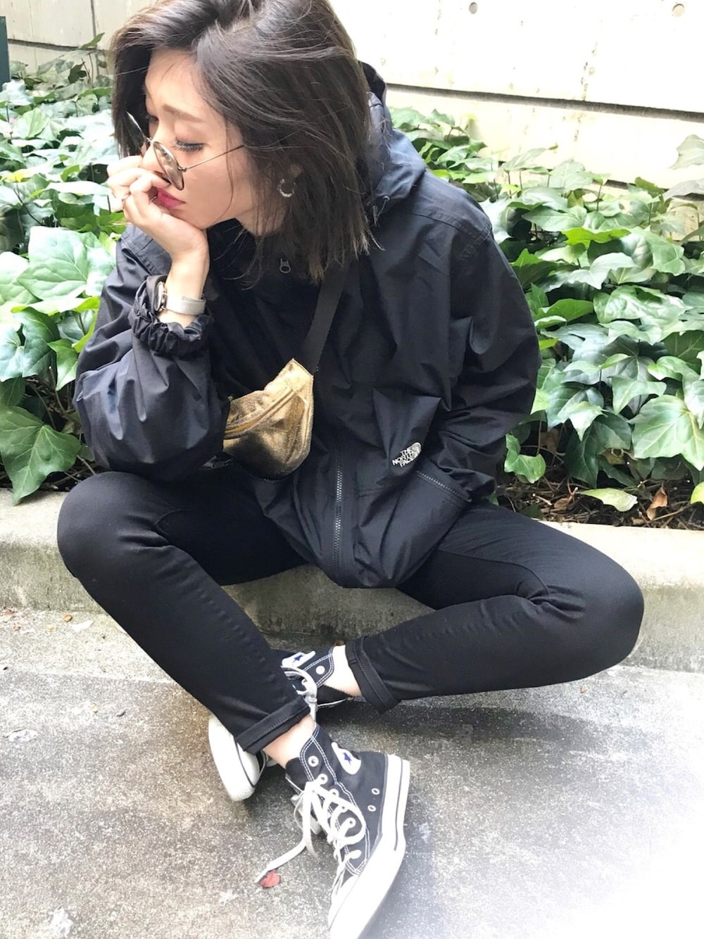 ゴールド系のバッグ、ブラック系のマウンテンパーカー、ブラック系のデニムパンツを着用したレディースの春コーディネートの1枚目の写真