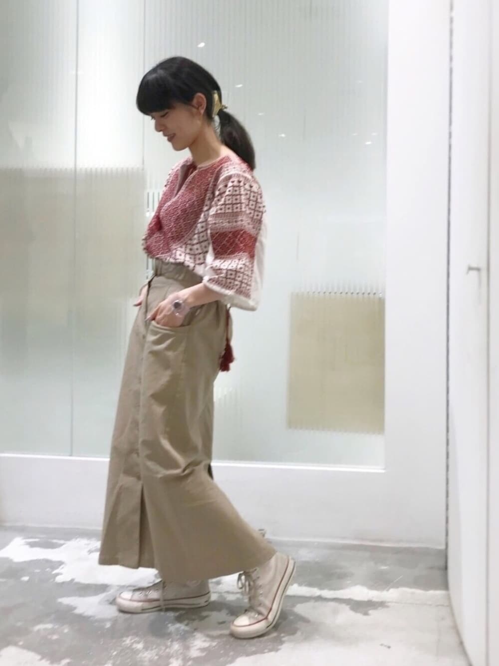 ベージュ系のスカート、ベージュ系のスニーカー、ホワイト系のチュニックを着用したレディースの夏コーディネートの1枚目の写真