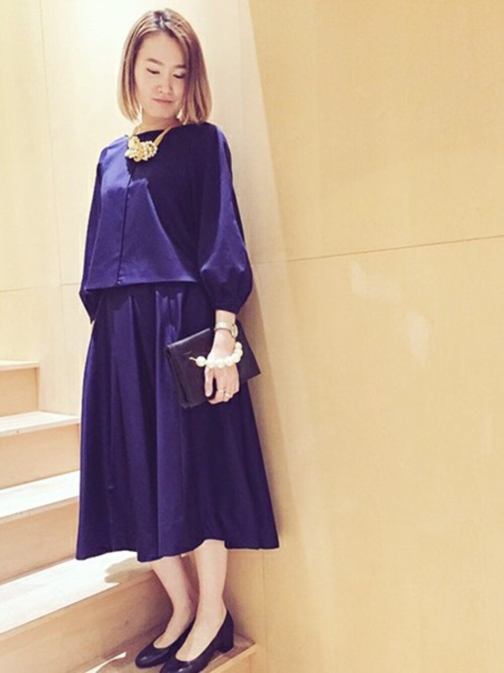 ブルー系のシャツ/ブラウス、ブラック系のクラッチバッグ、ブルー系のスカートを着用したレディースの春コーディネートの1枚目の写真