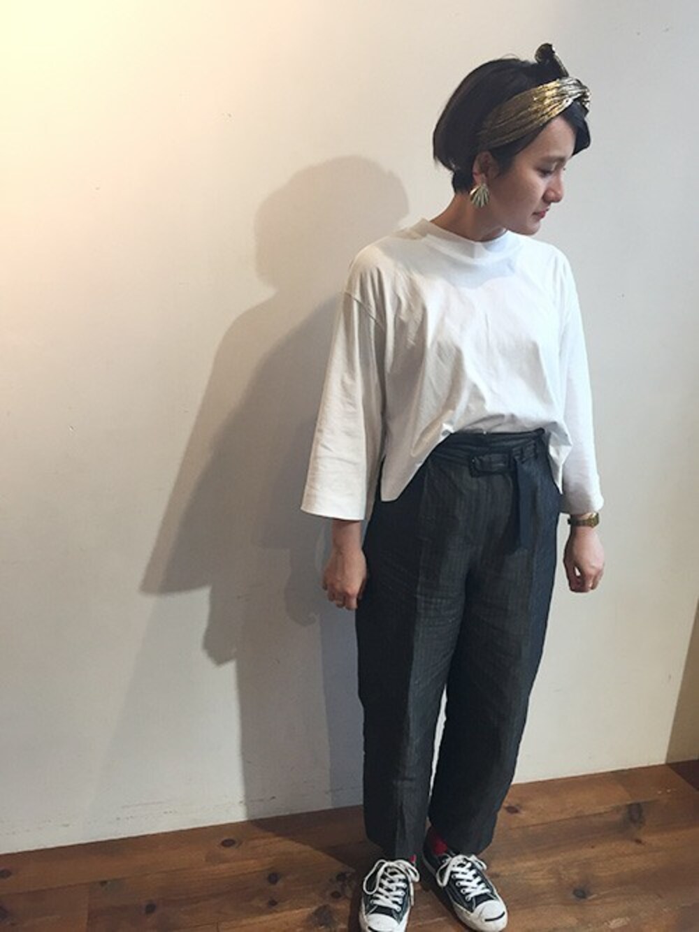 グレー系のスラックス、ゴールド系のイヤリング、ゴールド系のヘアバンドを着用したレディースの春コーディネートの1枚目の写真