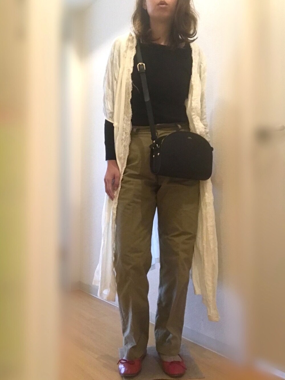 ホワイト系のワンピース、ブラック系のニット/セーター、ベージュ系のチノパンツを着用したレディースの春コーディネートの1枚目の写真