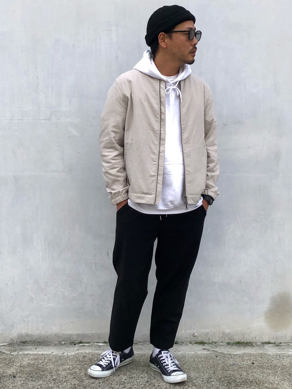 グレー系のブルゾン、ブラック系のスラックス、ホワイト系のパーカーを着用したメンズの春コーディネートの1枚目の写真