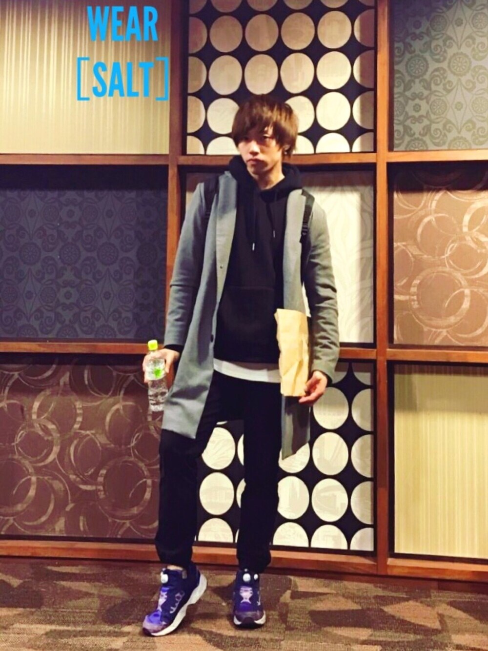 グレー系のチェスターコート、パープル系のスニーカー、ホワイト系のTシャツ/カットソーを着用したメンズの冬コーディネートの1枚目の写真