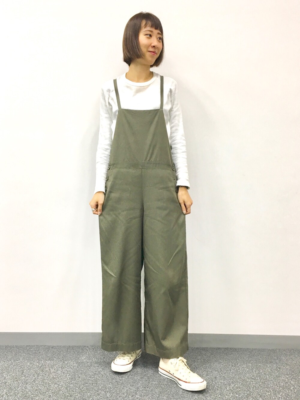 グリーン系のサロペット/オーバーオール、ホワイト系のTシャツ/カットソー、ホワイト系のスニーカーを着用したレディースの春コーディネートの1枚目の写真