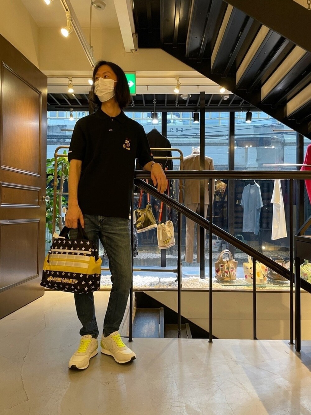 ブラック系のポロシャツ、ブラック系のバッグ、ホワイト系のスニーカーを着用したメンズの春コーディネートの1枚目の写真