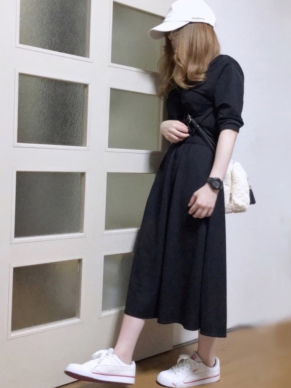 ブラック系のワンピース、ホワイト系のショルダーバッグ、ホワイト系のスニーカーを着用したレディースの秋コーディネートの1枚目の写真