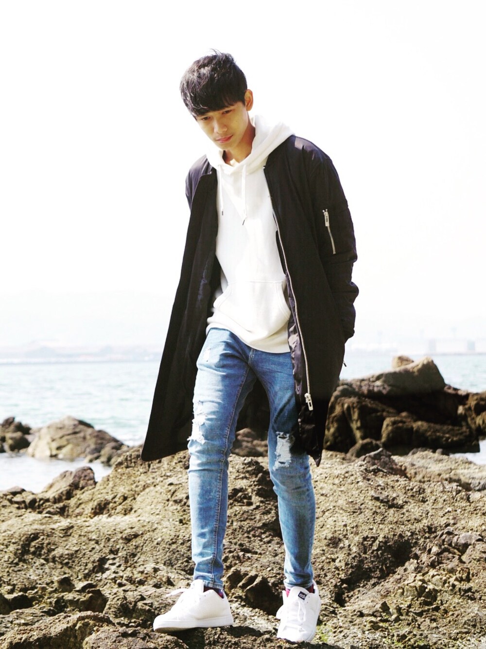 ホワイト系のスニーカー、ブルー系のデニムパンツ、ブラック系のMA-1を着用したメンズの春コーディネートの1枚目の写真