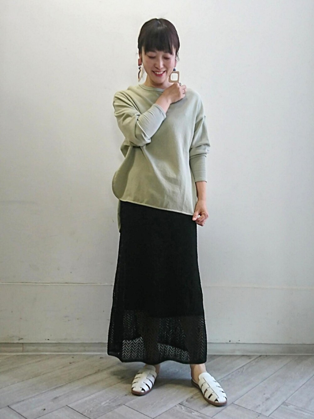 ホワイト系のサンダル、ブラック系のスカート、グリーン系のスウェットを着用したレディースの春コーディネートの1枚目の写真