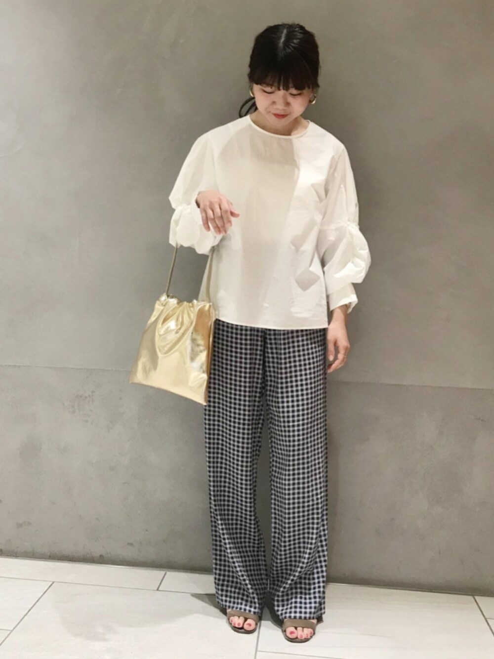 ホワイト系のシャツ/ブラウス、ゴールド系のショルダーバッグ、ブルー系のパンツを着用したレディースの春コーディネートの1枚目の写真