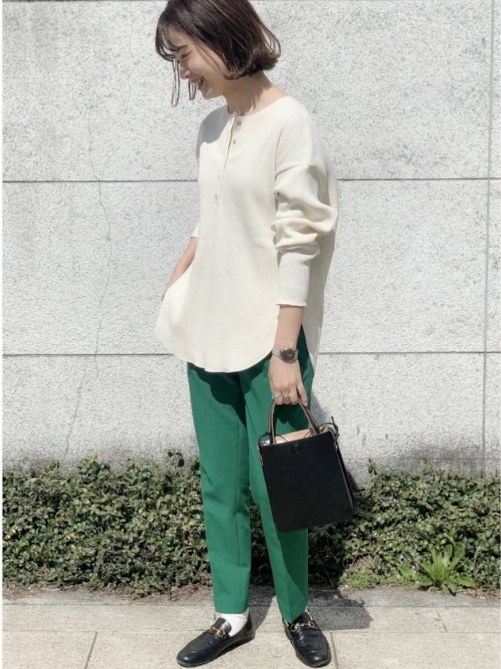 ブラック系のシューズ、ブラック系のショルダーバッグ、グリーン系のスラックスを着用したレディースの春コーディネートの1枚目の写真