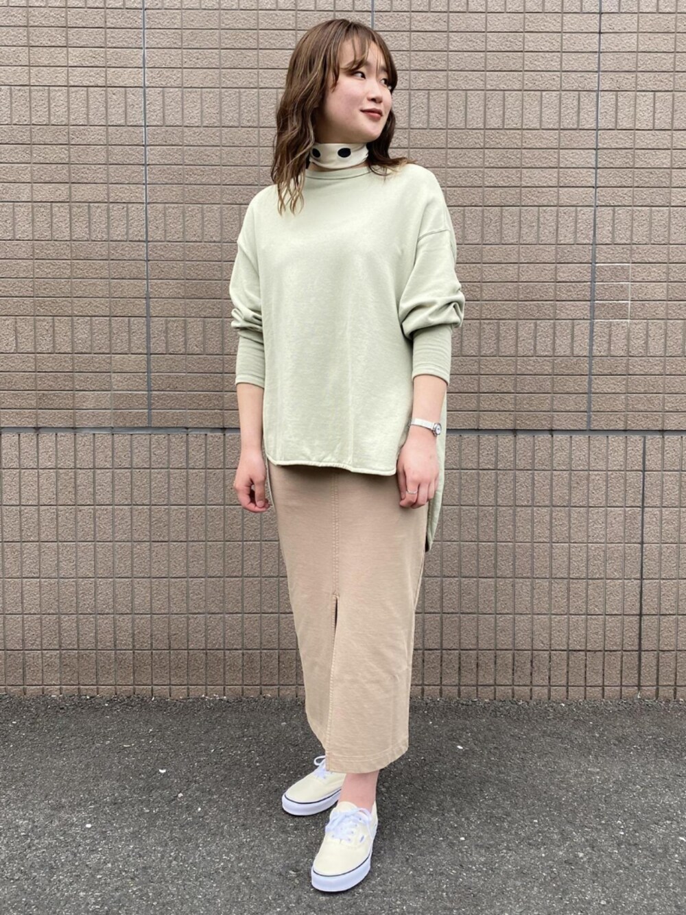 ホワイト系のスニーカー、ベージュ系のスカート、グリーン系のスウェットを着用したレディースの春コーディネートの1枚目の写真