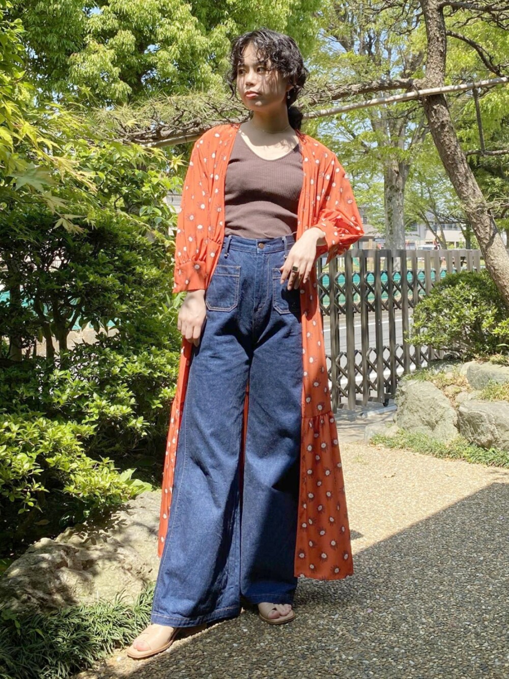 オレンジ系のワンピース、ブルー系のデニムパンツ、ベージュ系のシューズを着用したレディースの春コーディネートの1枚目の写真
