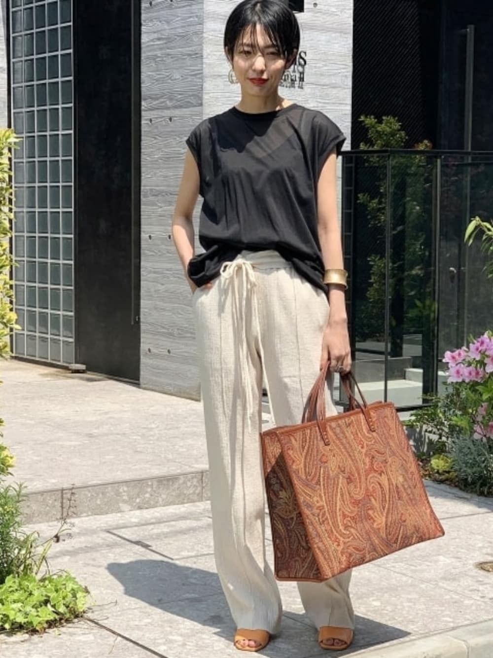 ブラック系のTシャツ/カットソー、オレンジ系のシューズ、レッド系のバッグを着用したレディースの春コーディネートの1枚目の写真