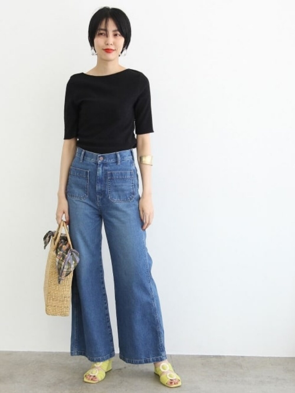 グリーン系のかごバッグ、グリーン系のシューズ、ブルー系のデニムパンツを着用したレディースの春コーディネートの1枚目の写真