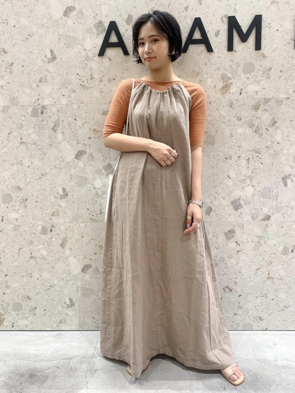 ベージュ系のシューズ、ベージュ系のワンピース/ドレス、オレンジ系のTシャツ/カットソーを着用したレディースの春コーディネートの1枚目の写真