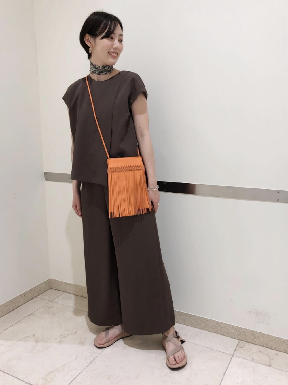 「アダムエロペ(ADAM ET ROPE')、Adam et Rope'、オールインワン、つなぎ、ブラウン、ブラウンコーデ、ショルダーバッグ、chaco、スポーツサンダル、スポサン」｜「NOMADISの【NOMADIS】Leather Fringe Bag（品番：EUX30240）（バッグ、オレンジ系）」を使った、ADAM ET ROPE' STAFFさん（レディース・165cm）の夏コーディネートの1枚目の写真