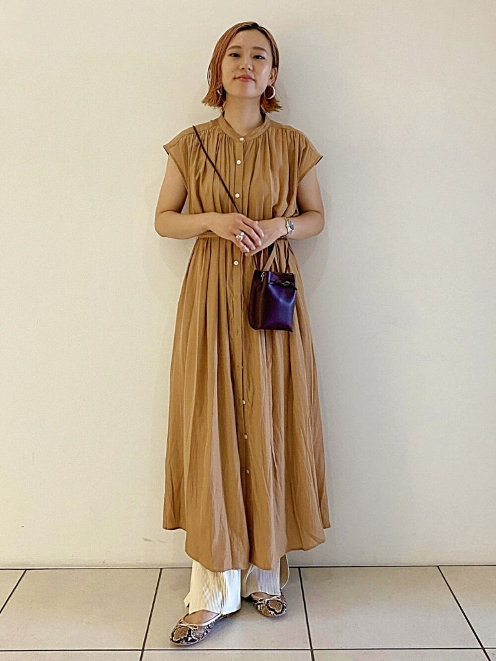 ベージュ系のワンピース、ベージュ系のバレエシューズ、レッド系のショルダーバッグを着用したレディースの秋コーディネートの1枚目の写真