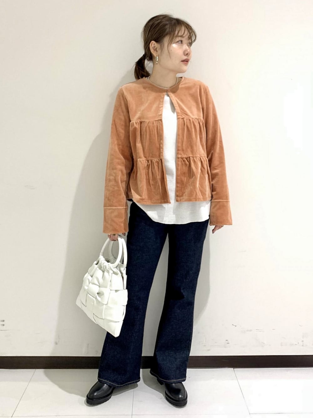 オレンジ系のカーディガン/ボレロ、ブルー系のデニムパンツ、ホワイト系のハンドバッグを着用したレディースの秋コーディネートの1枚目の写真