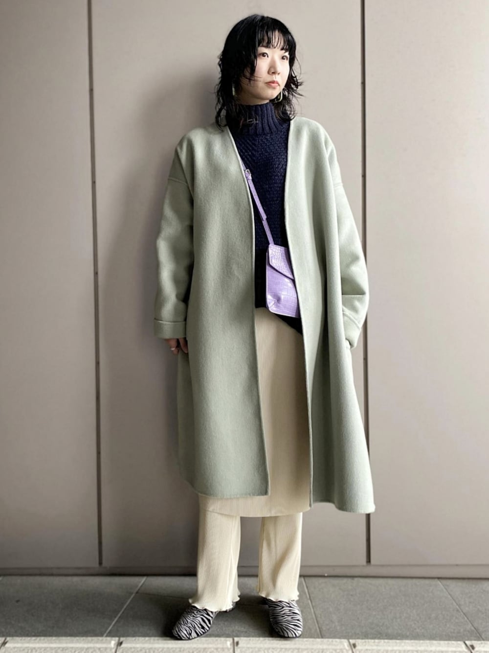 グリーン系のその他アウター、ブルー系のニット/セーター、パープル系のショルダーバッグを着用したレディースの冬コーディネートの1枚目の写真