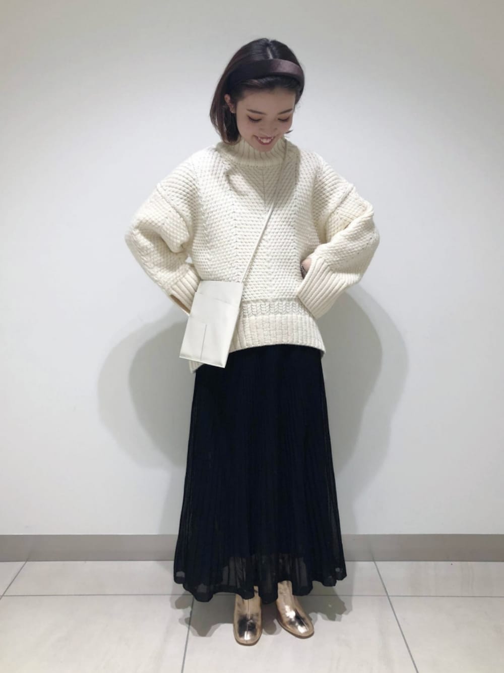 ホワイト系のショルダーバッグ、ブラック系のスカート、その他のブーツを着用したレディースの冬コーディネートの1枚目の写真