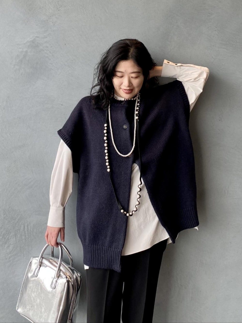 ブルー系のニット/セーター、シルバー系のボストンバッグ、ホワイト系のシャツ/ブラウスを着用したレディースの冬コーディネートの1枚目の写真