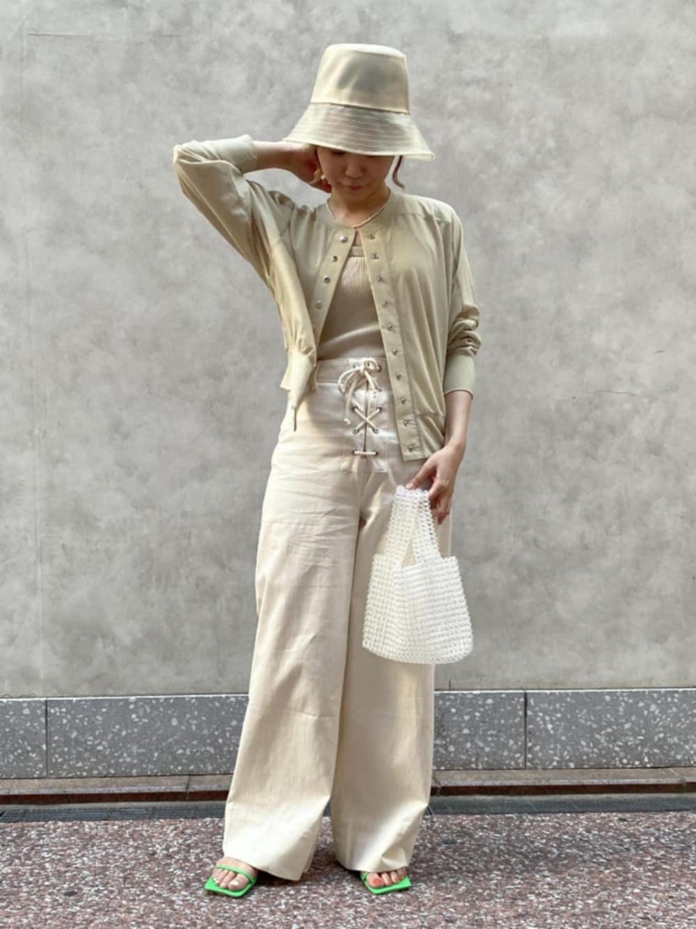 ホワイト系のタンクトップ、ホワイト系のパンツ、グリーン系のサンダルを着用したレディースの春コーディネートの1枚目の写真