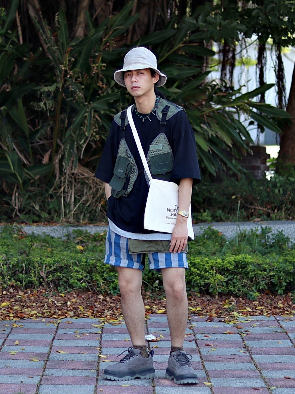 グリーン系のベスト、グレー系のその他シューズ、ブラック系のTシャツ/カットソーを着用したメンズの夏コーディネートの1枚目の写真