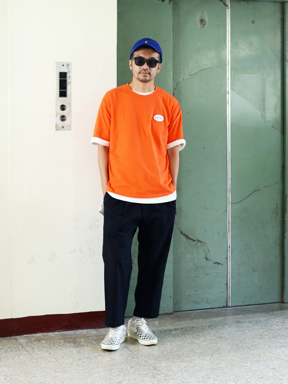 オレンジ系のTシャツ/カットソー、ブルー系のチノパンツを着用したメンズの春コーディネートの1枚目の写真