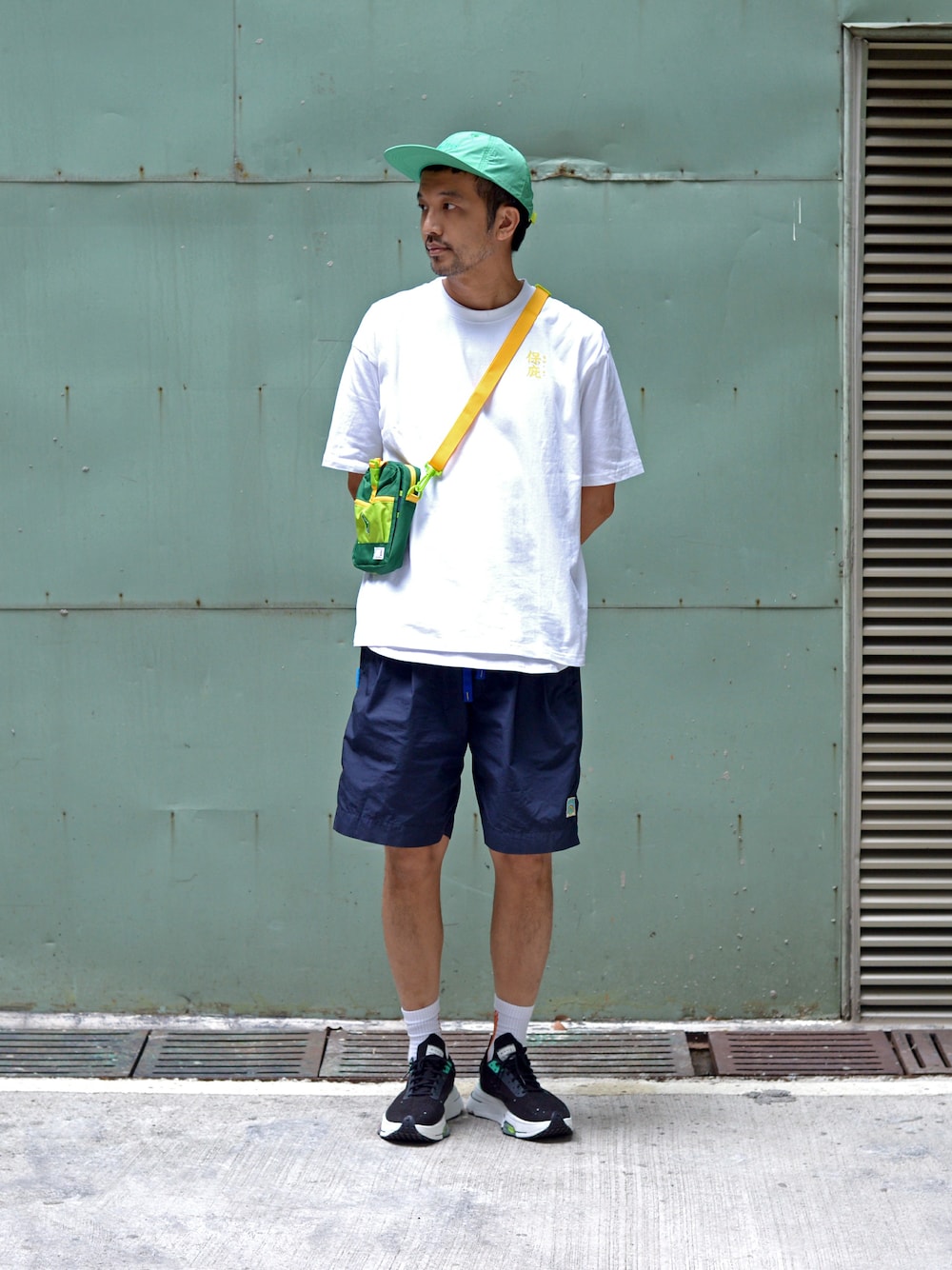 グリーン系のショルダーバッグ、ホワイト系のTシャツ/カットソーを着用したメンズの夏コーディネートの1枚目の写真