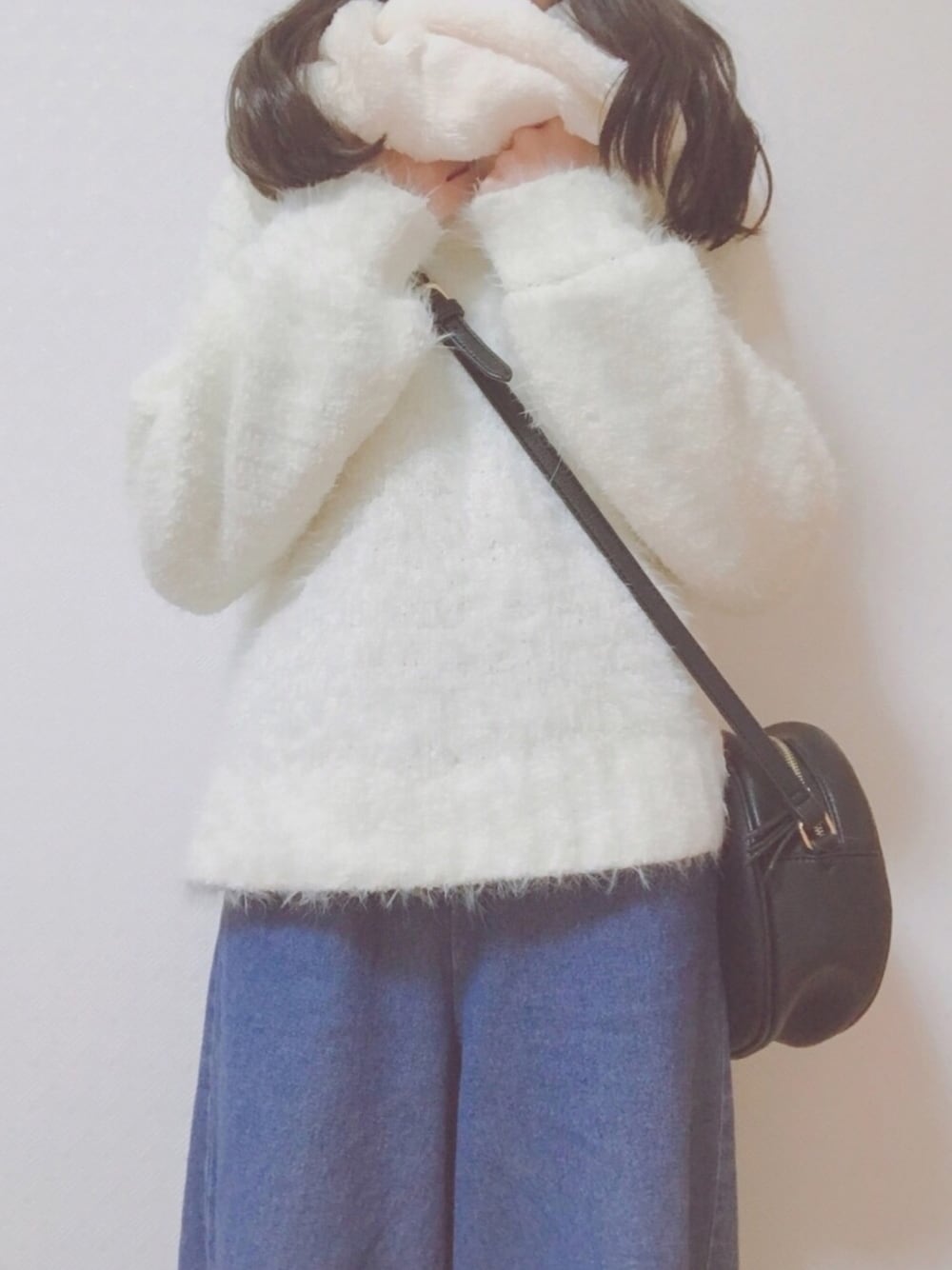 ホワイト系のニット/セーター、ブラック系のショルダーバッグ、ブルー系のパンツを着用したレディースの冬コーディネートの1枚目の写真