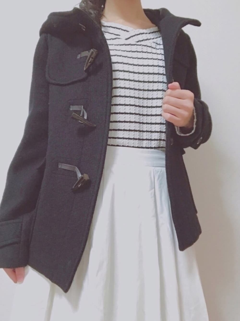 ホワイト系のスカート、ブルー系のダッフルコート、ホワイト系のTシャツ/カットソーを着用したレディースの冬コーディネートの1枚目の写真