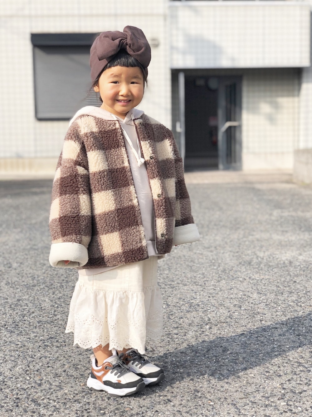 ブラウン系のジャケット/アウター、ベージュ系のパーカー、ホワイト系のスカートを着用したキッズの冬コーディネートの1枚目の写真