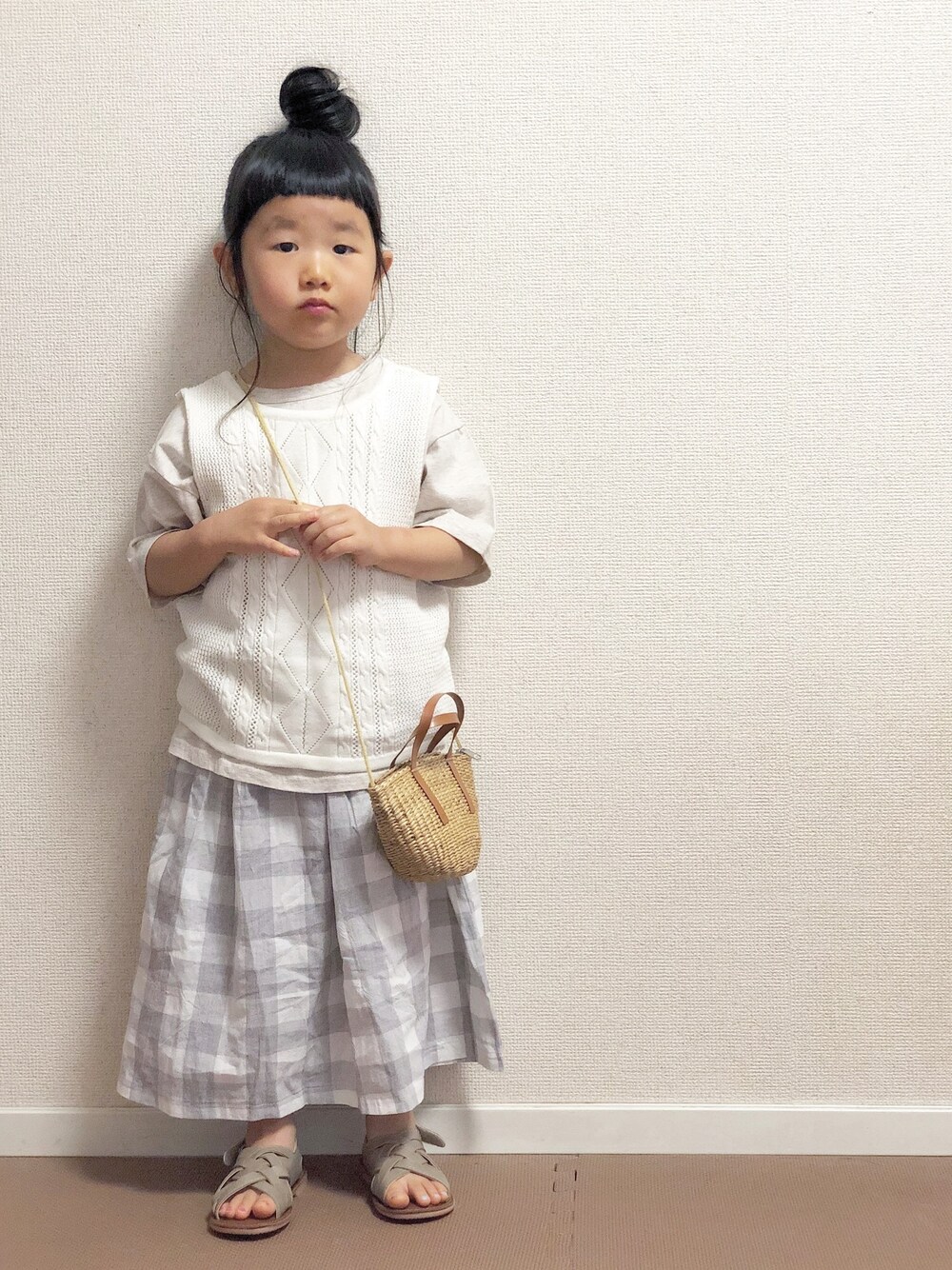 ホワイト系のニット/セーター、ベージュ系のTシャツ/カットソー、グレー系のスカートを着用したキッズの春コーディネートの1枚目の写真