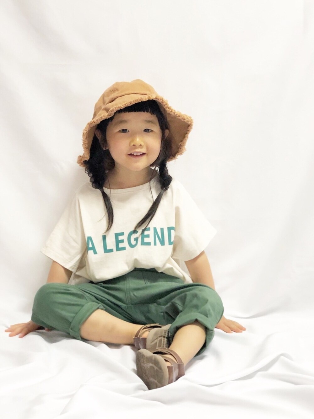 ホワイト系のTシャツ/カットソー、グリーン系のその他パンツ、ブラウン系のサンダルを着用したキッズの春コーディネートの1枚目の写真