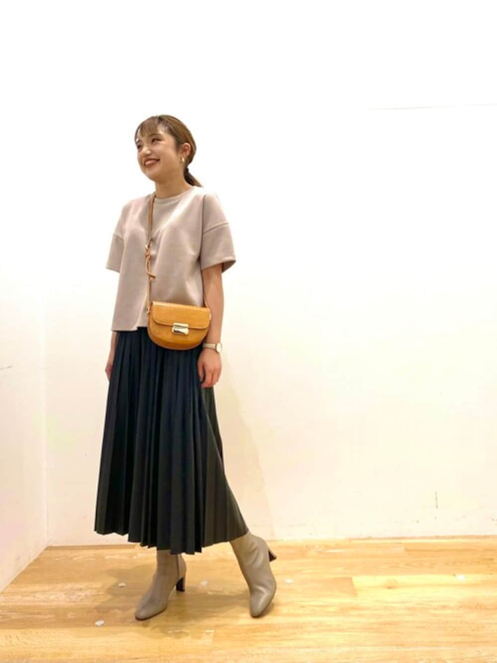 ベージュ系のTシャツ/カットソー、ブラック系のスカート、ベージュ系のブーツを着用したレディースの夏コーディネートの1枚目の写真