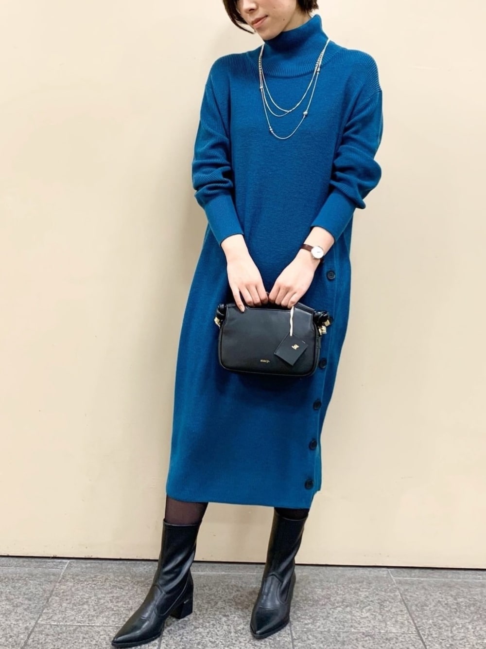 ブルー系のワンピース、ブラック系のブーツ、ゴールド系のネックレスを着用したレディースの冬コーディネートの1枚目の写真