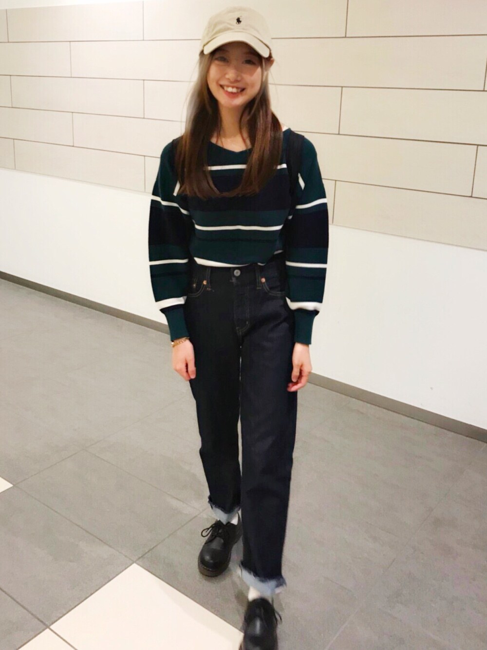 グリーン系のニット/セーター、ブルー系のデニムパンツ、ブラック系のドレスシューズを着用したレディースの秋コーディネートの1枚目の写真