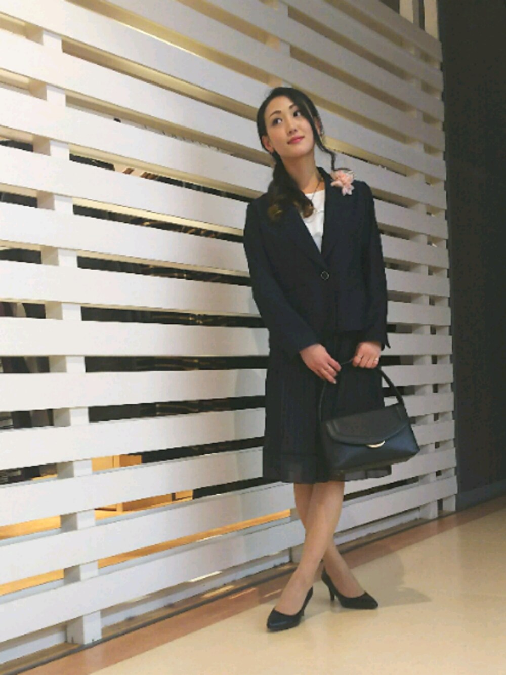 ブラック系のパンプス、ブラック系のショルダーバッグ、ブルー系のスカートを着用したレディースの冬コーディネートの1枚目の写真