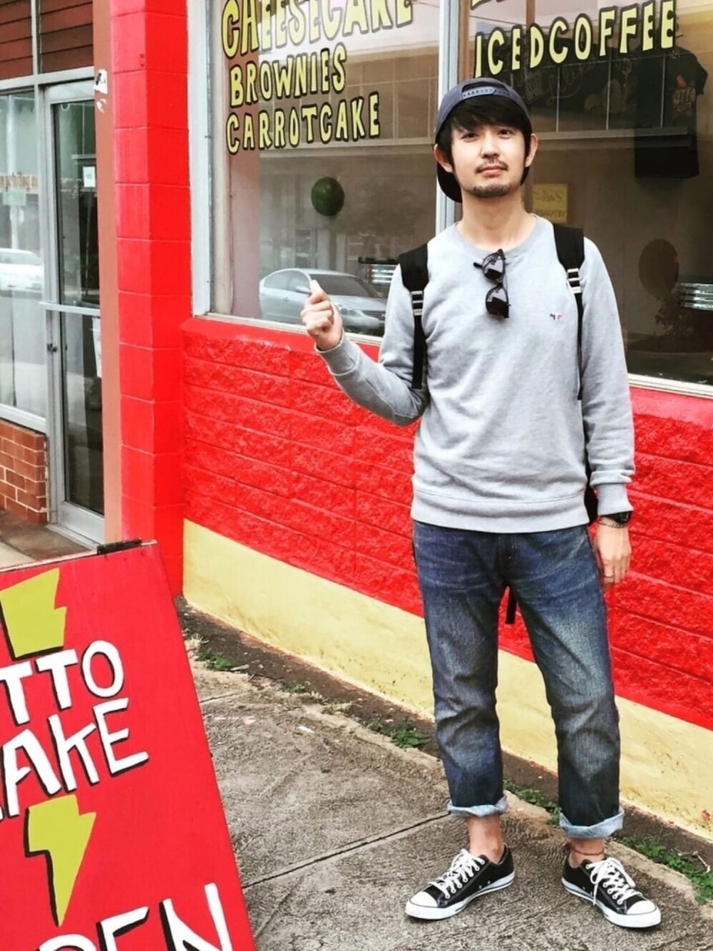 グレー系のスウェット、ブルー系のデニムパンツ、ブラック系のバックパック/リュックを着用したメンズの春コーディネートの1枚目の写真