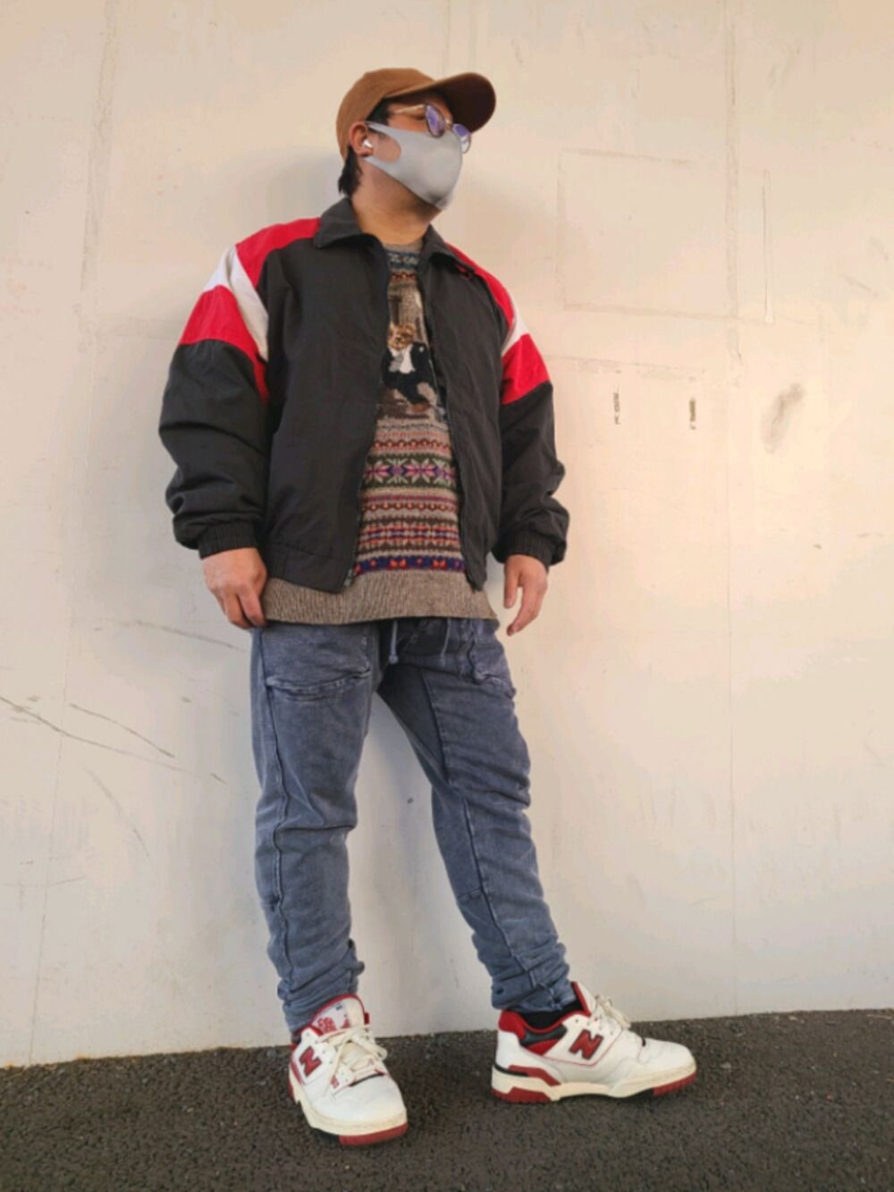 レッド系のナイロンジャケット、ブラウン系のニット/セーター、ブルー系のスウェットパンツを着用したメンズの冬コーディネートの1枚目の写真