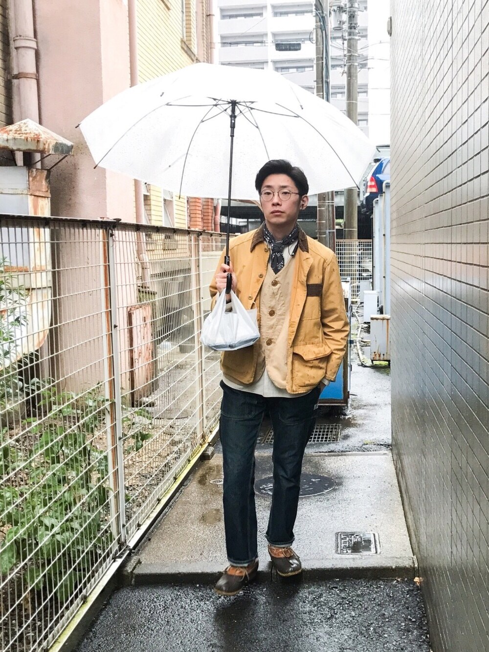 ブラウン系のベスト、ブルー系のデニムパンツ、ブラウン系のレインシューズを着用したメンズの冬コーディネートの1枚目の写真