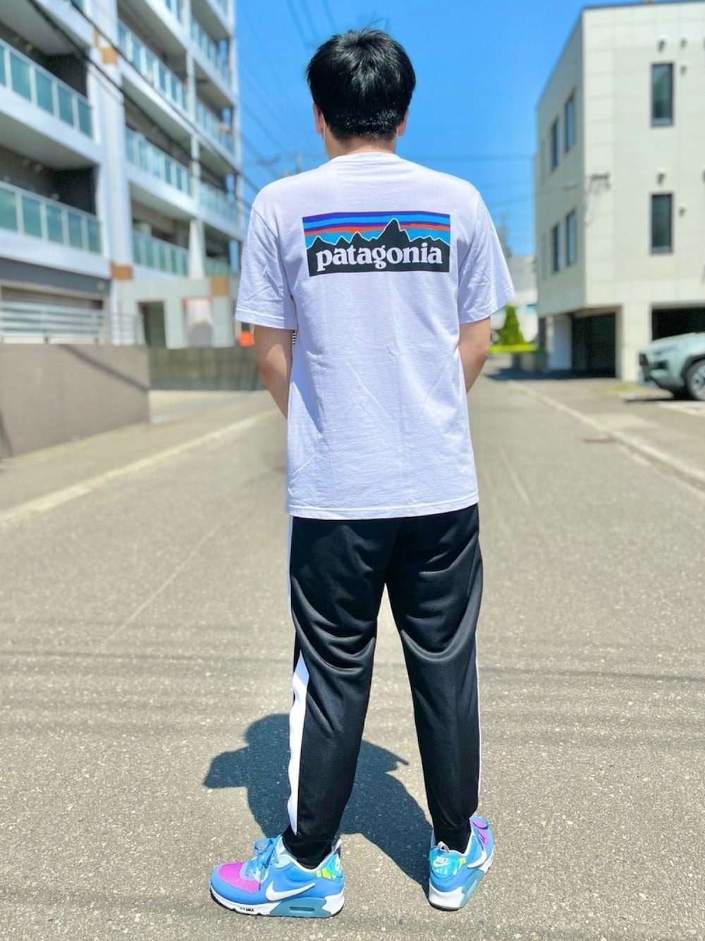 ホワイト系のTシャツ/カットソー、ブラック系のその他パンツ、ブルー系のスニーカーを着用したメンズの夏コーディネートの1枚目の写真