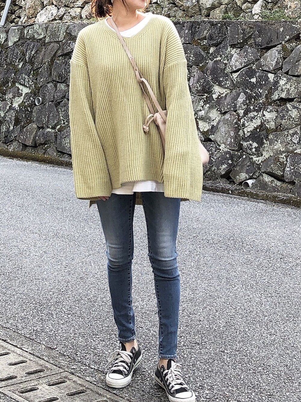 ベージュ系のショルダーバッグ、イエロー系のニット/セーター、ブルー系のデニムパンツを着用したレディースの冬コーディネートの1枚目の写真