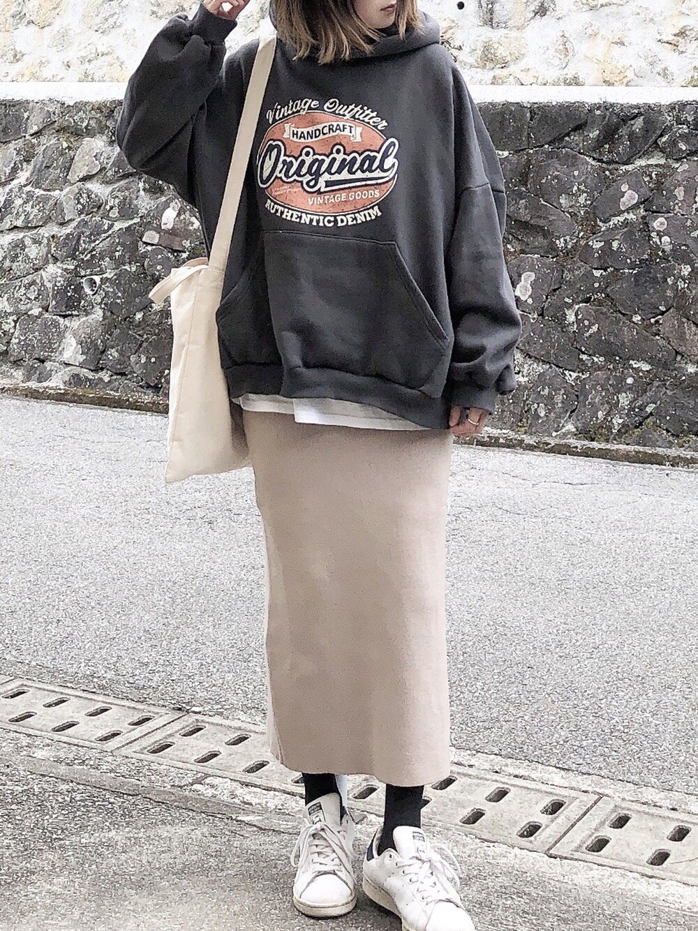 グレー系のパーカー、ベージュ系のショルダーバッグ、ベージュ系のスカートを着用したレディースの冬コーディネートの1枚目の写真