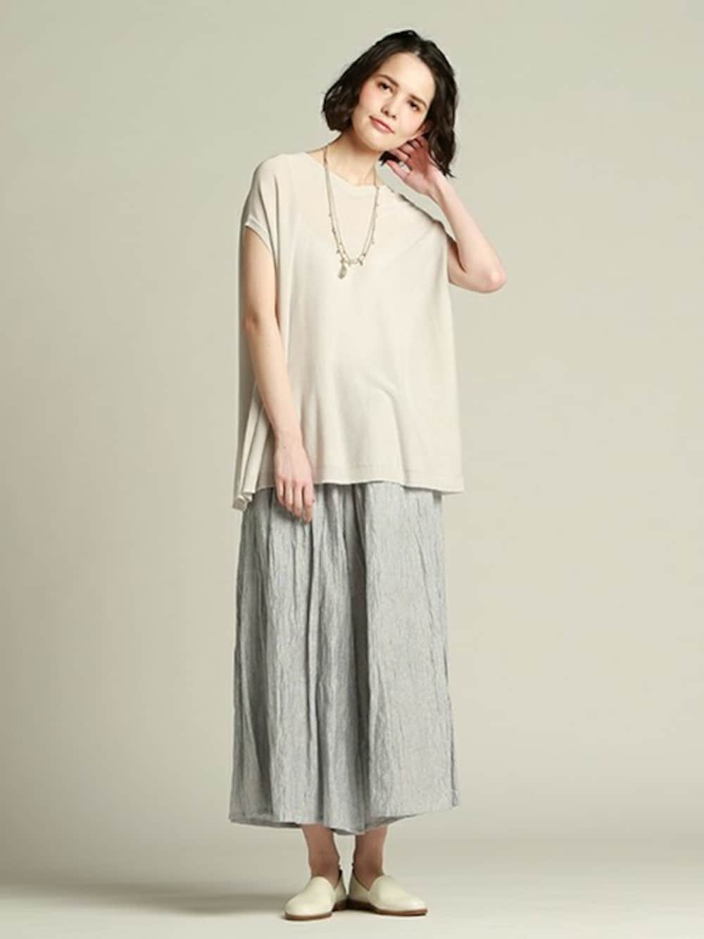 グレー系のニット/セーター、ホワイト系のその他パンツを着用したレディースの春コーディネートの1枚目の写真