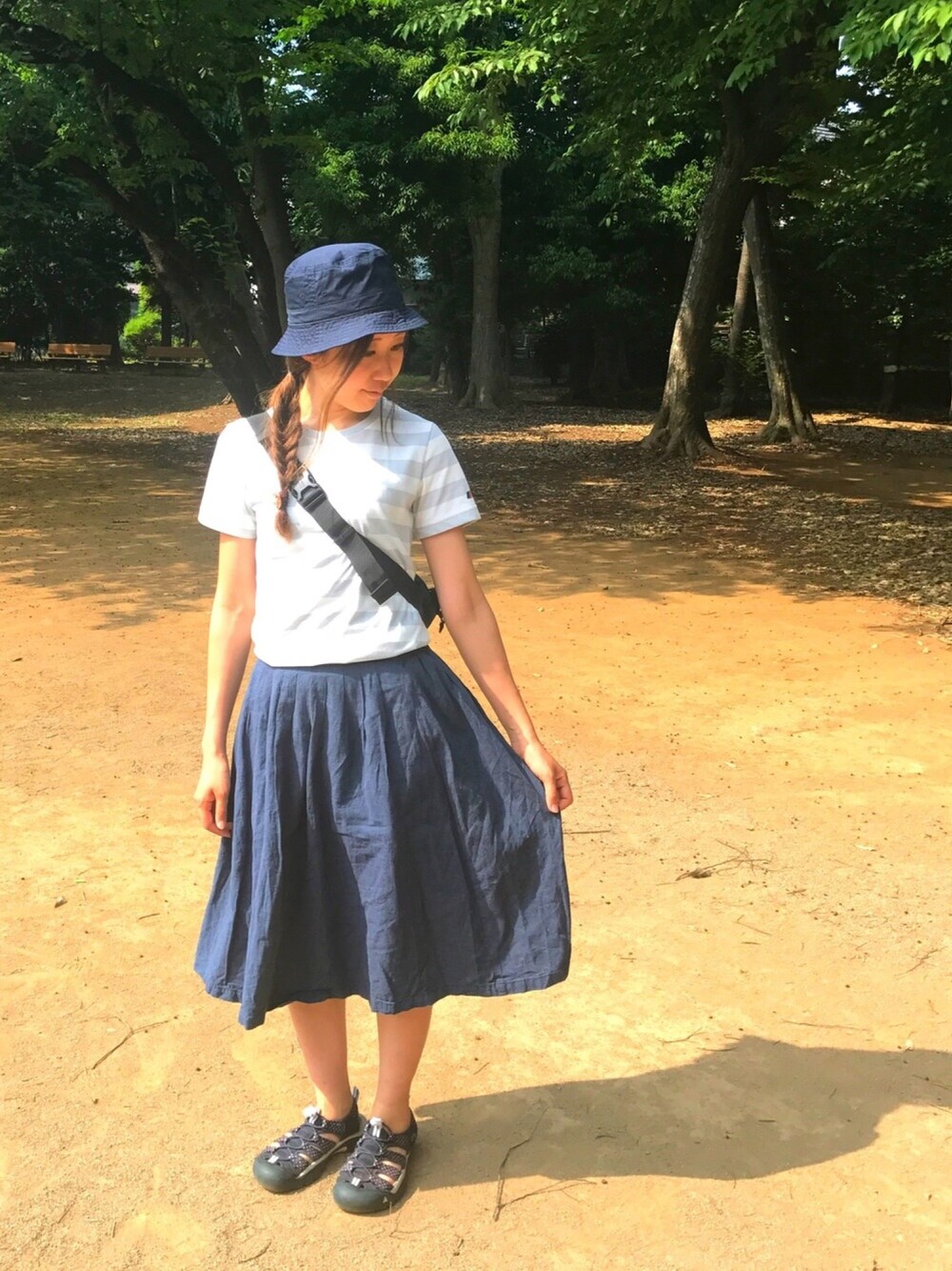 グレー系のTシャツ/カットソー、ブラック系のボディバッグ/ウエストポーチ、ブルー系のハットを着用したレディースの夏コーディネートの1枚目の写真