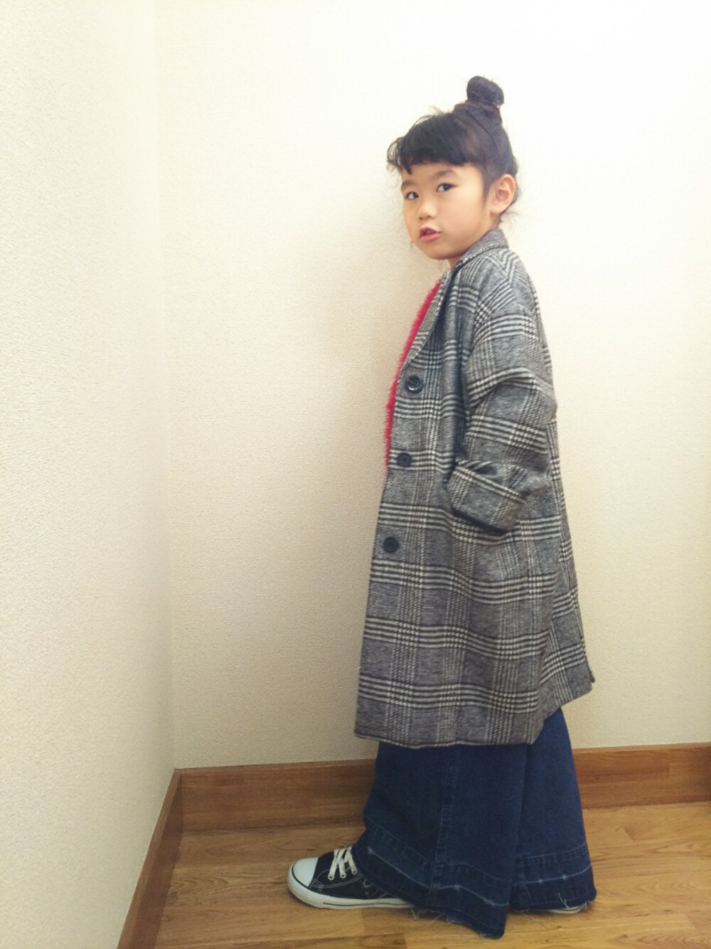 グレー系のチェスターコート、ブルー系のデニムパンツ、レッド系のワンピースを着用したキッズの冬コーディネートの1枚目の写真