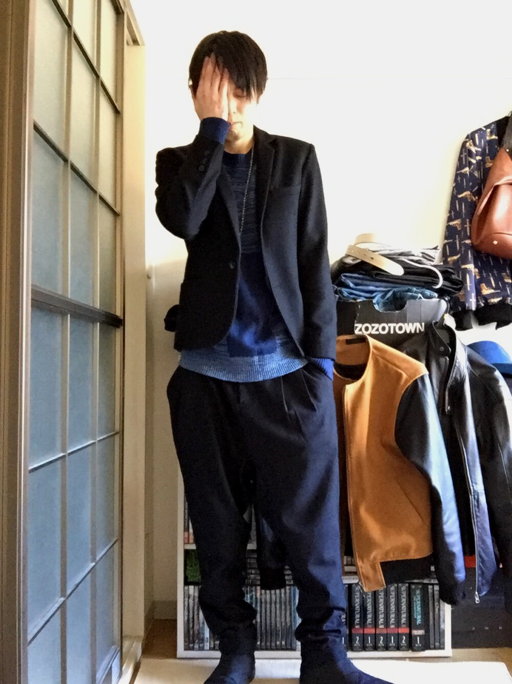 ブラック系のテーラードジャケット、ブルー系のニット/セーター、ブラック系のスラックスを着用したメンズの冬コーディネートの1枚目の写真